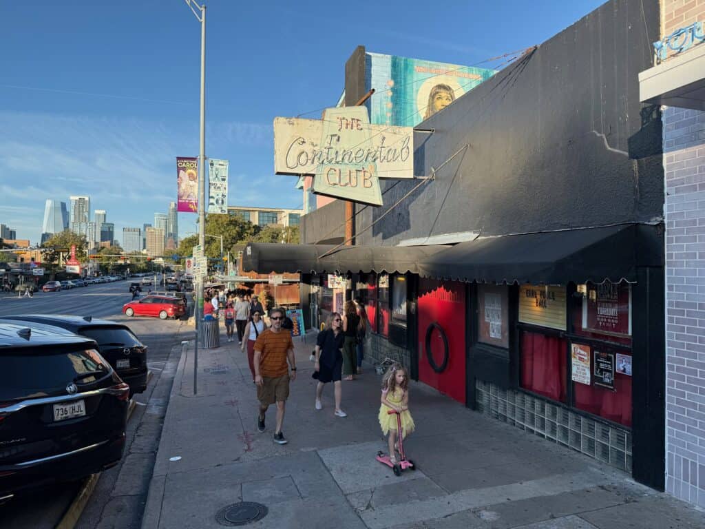 The Continental Club's vintage neon sign on South Congress Avenue with the downtown Austin skyline in the distance