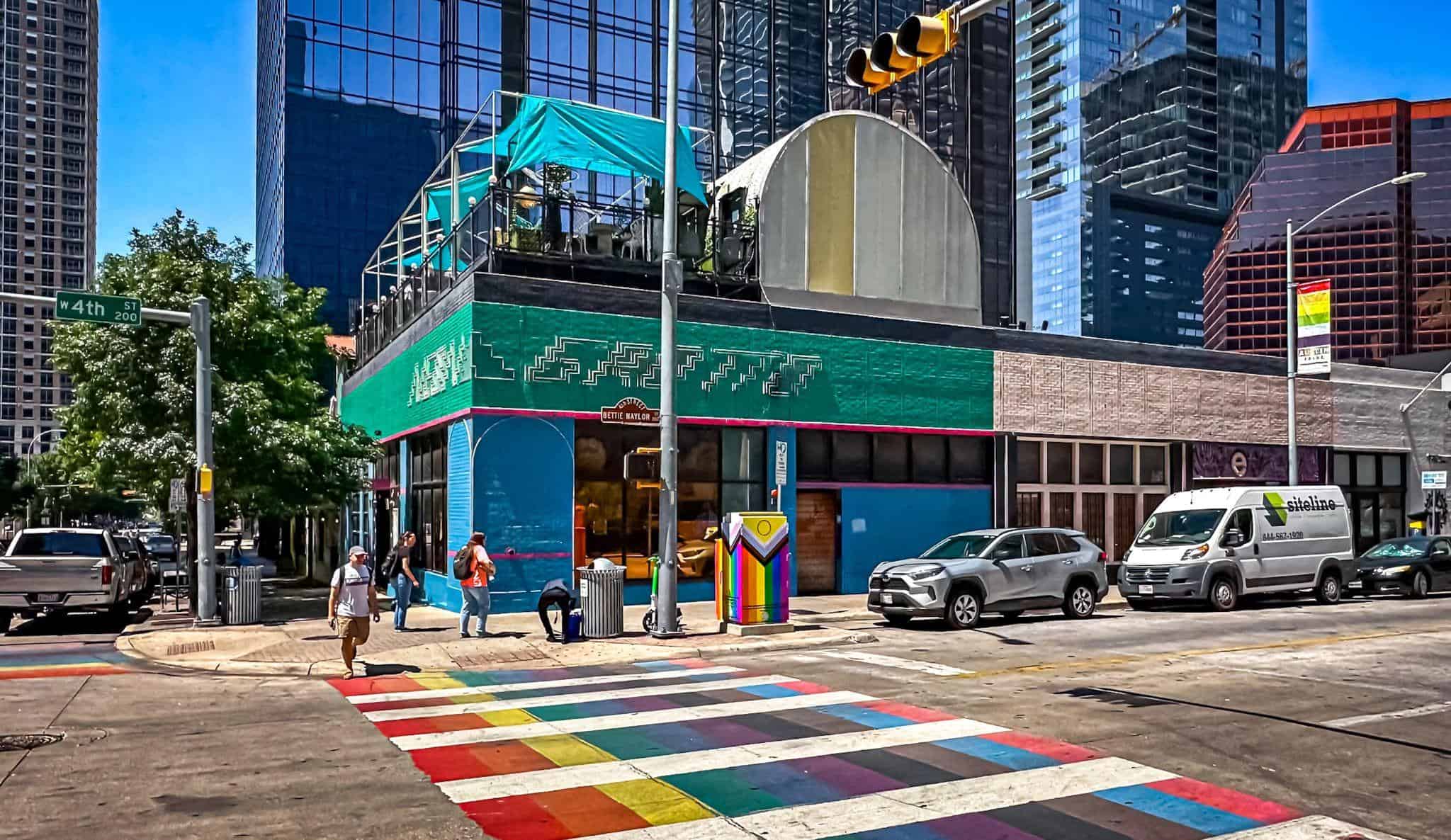 A rainbow-painted crosswalk at West 4th Street in downtown Austin on a bright, clear day