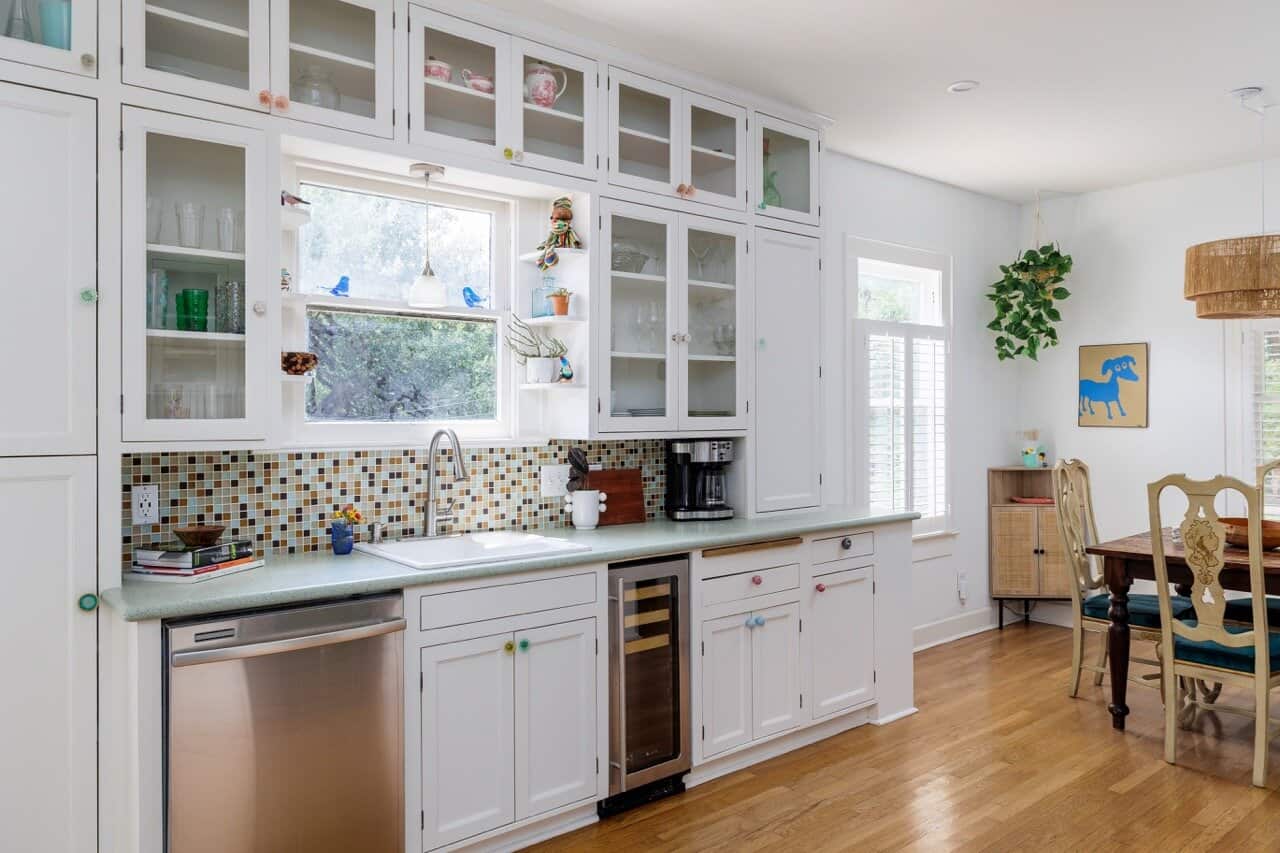 The kitchen at SoCo Cottage with white cabinetry and a colorful tile backsplash