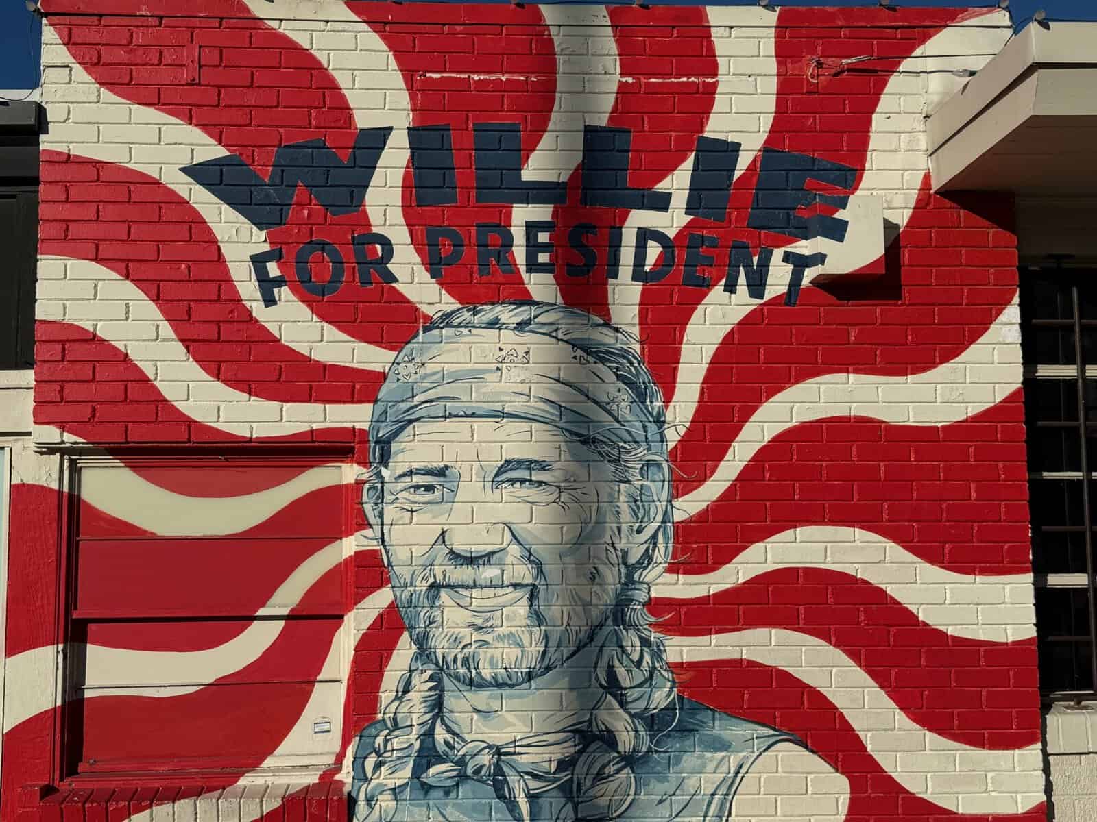 The 'Willie for President' mural, a portrait on a red-and-white sunburst brick wall on South Congress Avenue in Austin