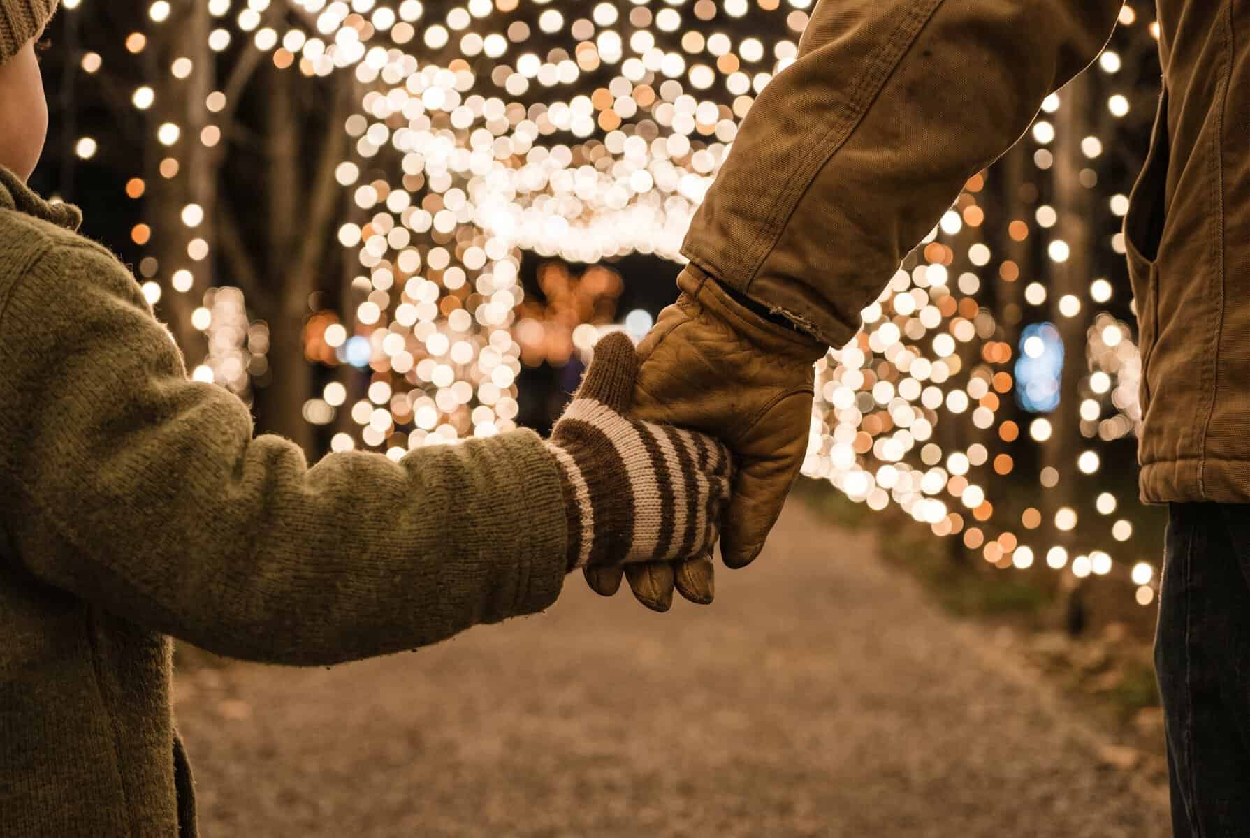 Things to Do in Austin in December (Holiday Guide) Parent and child in mittens holding hands on a path lined with holiday lights